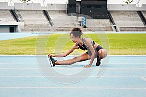 Woman, fitness and stretching body on stadium track for running, exercise or workout. Active female person or athlete in