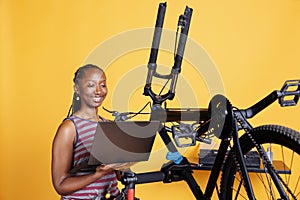 Woman fixes bike with tools and laptop