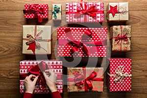 Woman fixing a bow on beautifuly wrapped vintage christmas presents on wooden background photo