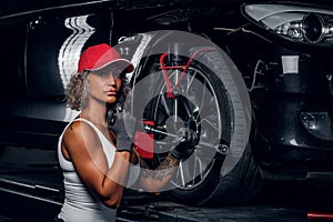 Woman is fixing car`s tyre in auto servis