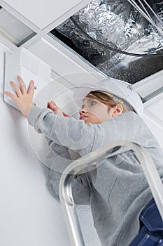 Woman fixing ceiling at home