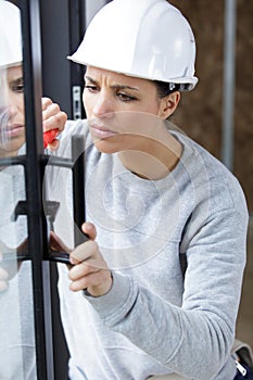 woman fixing door with screwdriver