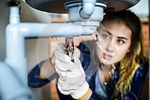 Woman fixing kitchen sink at home