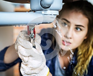 Woman fixing kitchen sink at home