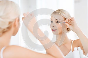 Woman fixing makeup with cotton swab at bathroom photo