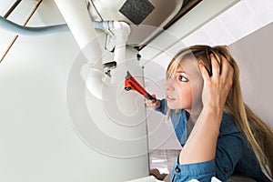 Woman Fixing Sink Pipe With Wrench In Kitchen