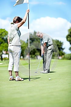 Woman with flag, old man or golfer on golf course for a birdie, putting stroke or exercise in retirement. Senior couple