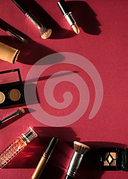 Woman flat lay makeup background with set of decorative cosmetics with dark shadows. Cream, lipstick, perfume, mascara and brush