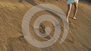 Woman flee on dune. Footprints on Sand. Sunset on Desert. Slow Motion.