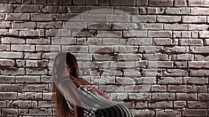 Woman flexible in high heels dance twerk against a brick wall. Slow motion