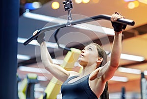 Woman flexing arm muscles on cable machine in gym