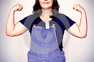 woman flexing biceps muscles dungarees