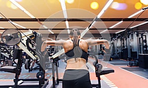 Woman flexing muscles on cable machine in gym