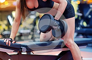 Woman flexing muscles with dumbbell in gym