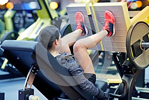 Woman flexing muscles on leg press machine in gym