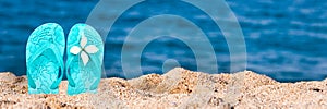 Woman flip flops stuck in the sand on a beach, panoramic summer background