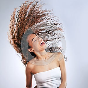 Woman, flip and hair in studio happy for healthy, volume and natural cosmetic care with treatment for curls. Girl, calm