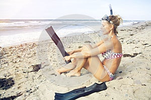 Woman with flippers sitting on the beach