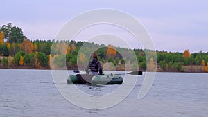 A woman floated on a rubber boat on a large lake in beautiful autumn forest.