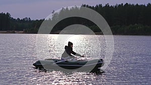 A woman floated on a rubber boat on a large lake in beautiful autumn forest.