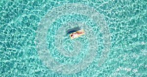 Woman floating on lilo inflatable mattress over blue transparent water surface in summer holiday vacation leisure activity. Female