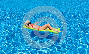 Woman floating on a mattress in a swimming pool