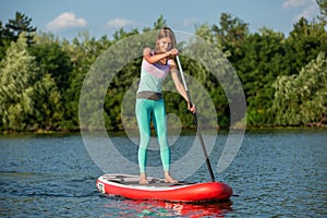 Woman is floating on a SUP board on sunny morning. Stand up paddle boarding - awesome active recreation during vacation. photo