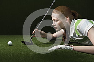 Woman On Floor Holding Golf Club Looking At Golf Ball