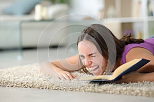 Woman on the floor laughing hilariously reading a book photo
