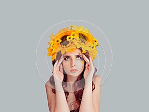 Woman with floral headband hands on temples head thinking deeply