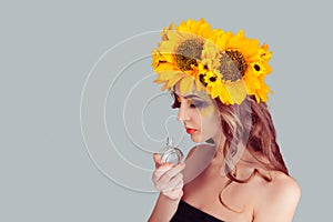 Woman with floral headband holding perfume bottle smelling aroma