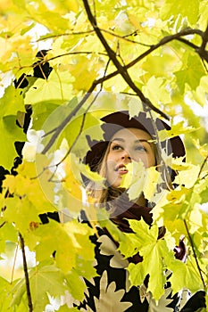 Woman in a floral patterned coat and wine red hat in the park, by the river. Happy girl, colorful autumn forest. Portrait of lady