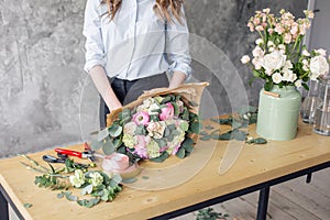 Woman florist creating beautiful bouquet in flower shop. Working in flower shop. Girl assistant or owner in floral