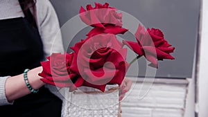 Woman florist creating a composition with red roses