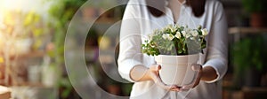 Woman florist holding pot with plant in flower shop