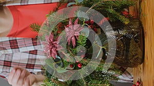 Woman florist making Christmas flower arrangement. Vertical video.