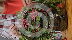 Woman florist making Christmas flower arrangement. Vertical video.