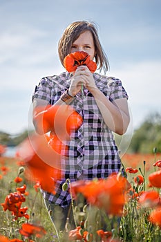 Woman on flower field sniffs bunch of poppies