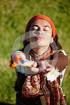 Woman, flower and grass for gypsy with plant in nature for summer, outdoor and adventure in garden. Young person, lady