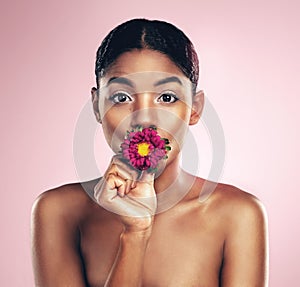 Woman, flower and portrait in studio for wellness with makeup on pink background for aesthetic or visual impact