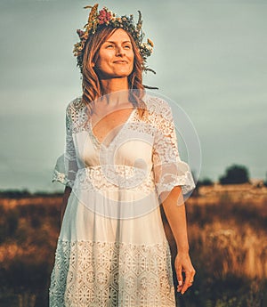 Woman in flower wreath on sunny meadow, Floral crown, symbol of summer solstice.