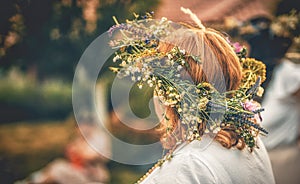 Woman in flower wreath on sunny meadow, Floral crown, symbol of summer solstice.