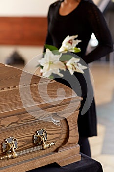 Woman with flowers and coffin at funeral