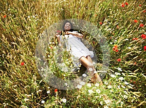 Woman, flowers and laying in field, portrait and smile in spring, vacation and sunshine in nature. Girl, happy and relax