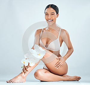 Woman, flowers and legs in studio for skincare, sustainable cosmetics and vegan beauty. Female person, orchids and