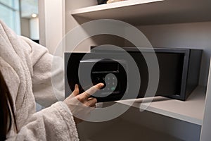 Woman in a fluffy terry bathrobe opens a portable safe