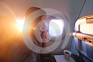 Woman Flying on an Airplane Wearing a Face Mask and Looking in Windo