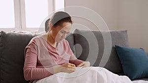 Woman fold towel and sit on sofa