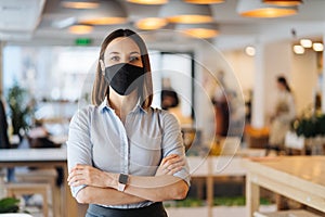 Woman with folded arms wearing mask indoors