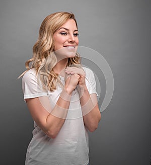 The woman folded her arms over her chest like during a prayer on gray background.